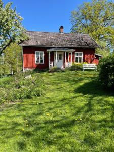 a red house with a grassy yard in front of it at SwedishCountryLiving / Skippers cottage in Köpmannebro