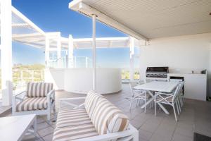 a patio with a table and chairs and a kitchen at Coastal Penthouse 3BR Luxe Living Over Kirra Beach in Gold Coast