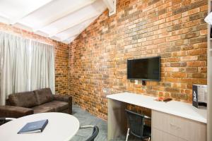 a room with a brick wall with a couch and a tv at Leisure Inn Hotel Rockingham in Rockingham