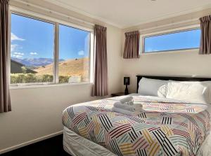 a bedroom with a bed with a view of the desert at Ashley Heights - Lake Tekapo in Lake Tekapo