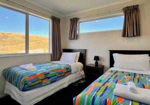 a bedroom with two beds and two windows at Ashley Heights - Lake Tekapo in Lake Tekapo