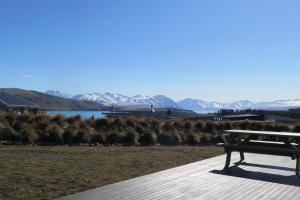 a bench sitting on a dock with a view of a lake at Ashley Heights - Lake Tekapo in Lake Tekapo