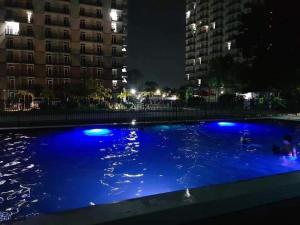 a large blue swimming pool at night with buildings at Mactan cozy nest 1619 in Lo-oc