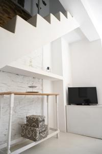 a white living room with a table and a tv at Terramare Villa's 3 in Kithnos