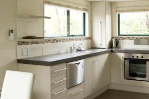 eine weiße Küche mit Spüle und Fenster in der Unterkunft A family friendly haven in Hanmer Springs