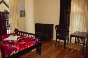 een slaapkamer met een bed, een stoel en een tafel bij Merry Villas in Kurseong