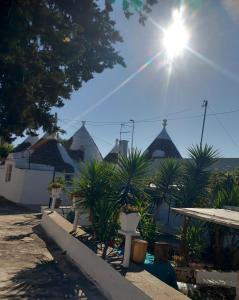 une rangée de maisons avec des palmiers et le soleil dans l'établissement Il trullo della nonna, à Martina Franca