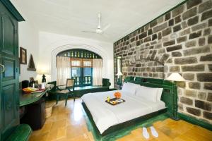 - une chambre avec un lit et un mur en pierre dans l'établissement Sparsa Resort Thiruvanamalai, à Tiruvannāmalai