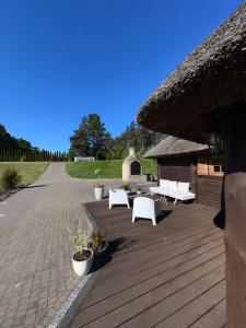 a patio with white benches and a thatch roof at Cabin by the pond in Wądołki Bućki