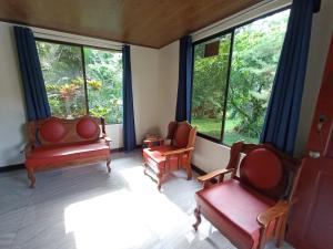 a living room with two chairs and large windows at Quinta Rincon Silvestre cerca de Volcán in Jabillos