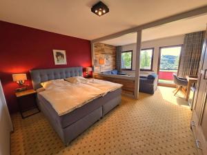 a bedroom with a large bed with a red wall at Berghotel Habbel und die Welt kann warten in Cobbenrode +40 photos