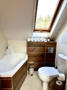a bathroom with a tub and a toilet and a window at Domek nad stawem in Wyszomierz Wielki