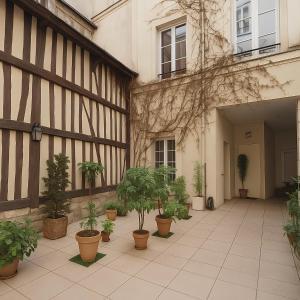 a courtyard with potted plants and a building at Malpalu St Maclou centre Rouen Linges et ménage inclus in Rouen