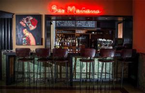 Un bar con taburetes marrones y un letrero de neón rojo. en Dream South Beach, by Hyatt, en Miami Beach