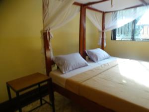a bedroom with a bed with a canopy and a table at Mgulani Lodge Hotel in Dar es Salaam