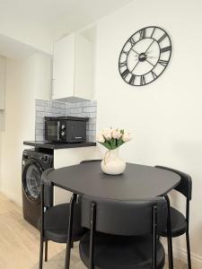 a kitchen with a table and a clock on the wall at 'The Elegant Comfort' - A Stunning Luxury 2-Bed Flat with Private Garden & Patio - Free Parking in Northampton