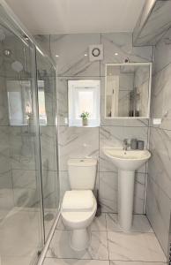 a white bathroom with a toilet and a sink at 'The Elegant Comfort' - A Stunning Luxury 2-Bed Flat with Private Garden & Patio - Free Parking in Northampton +40 photos