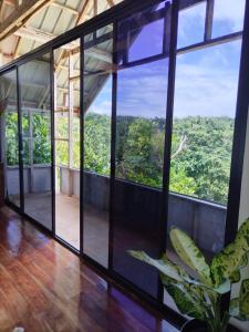ein offener Raum mit Blick auf den Wald durch die Fenster in der Unterkunft Siquijor Hilltop House Near Cambugahay Falls in Lazi