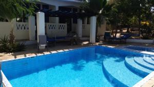 a large swimming pool with stairs next to a house at Diani Serena House in Ukunda