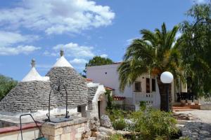 ein Haus mit einer Palme davor in der Unterkunft Villa dei Tigli - trulli e relax in Castellana Grotte
