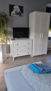 a bedroom with a white dresser with a flat screen tv at Stadtnah an der Förde 7502 E in Flensburg