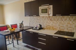 a kitchen with black cabinets and a counter top with a microwave at Hotel Inter Tete in Vila-de-Santiago-Maior