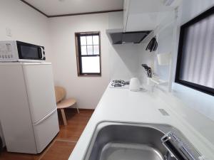 a white kitchen with a sink and a refrigerator at Chiba Gateway House in Chiba