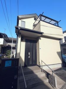 a white house with a door and some stairs at Chiba Gateway House in Chiba