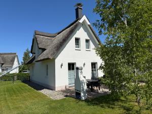 una casa bianca con tetto di paglia di Reethaus Sonnenwiese, Haus am Meer mit eingezäuntem Garten, Hunde herzlich willkommen a Glowe