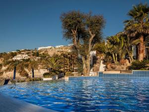 a swimming pool with palm trees and a hill in the background at Miramare Sea Resort & Spa in Ischia