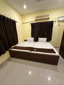 a bedroom with a large bed with black curtains at Five stones By Earth Hotel Vadapalani in Chennai +1 photo