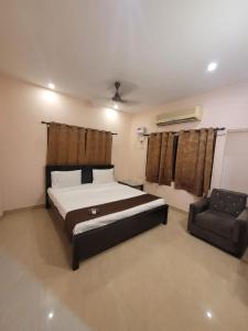 a bedroom with a large bed and a chair at Five stones By Earth Hotel Vadapalani in Chennai