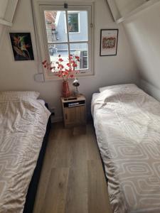 zwei Betten in einem kleinen Zimmer mit Fenster in der Unterkunft Bed & Breakfast De Punt in Monnickendam