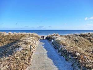Dos personas caminando por un sendero hacia la playa. en Ferienzimmer Gleißner, en Ahlbeck