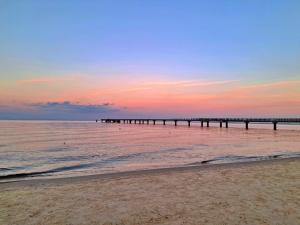 un muelle se extiende sobre el océano al atardecer en Ferienzimmer Gleißner, en Ahlbeck