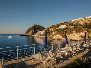 a group of chairs and blue umbrellas next to the water at Miramare Sea Resort & Spa in Ischia