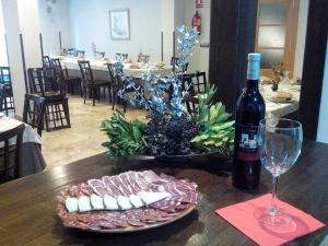 a table with a plate of meat and a bottle of wine at Hotel Peña Escrita in Fuencaliente