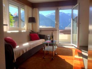 un soggiorno con divano, tavolo e finestre di Bright apartment close to center a Grächen