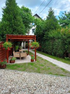 a wooden pergola with a table and chairs in a yard at Pokoje gościnne u Zosi Krościenko in Krościenko