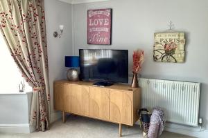 a flat screen tv sitting on top of a wooden cabinet at Lorton Villa with a Log Burner in Saint Helens