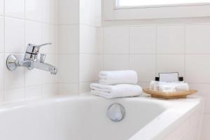 a white bathroom with a tub and a sink at Wyndham Garden Donaueschingen in Donaueschingen