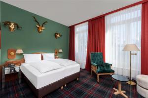 a hotel room with a bed and a chair at Wyndham Garden Donaueschingen in Donaueschingen +37 photos