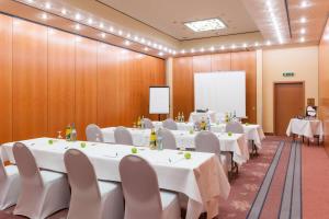 a conference room with white tables and chairs and a whiteboard at Wyndham Garden Donaueschingen in Donaueschingen