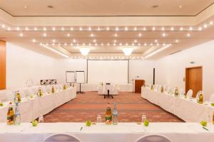 a large room with white tables and a projection screen at Wyndham Garden Donaueschingen in Donaueschingen