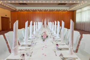 a long table with white tables and chairs in a room at Wyndham Garden Donaueschingen in Donaueschingen