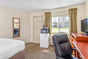 a hotel room with a bed and a desk and a television at Travelodge by Wyndham Gananoque in Gananoque