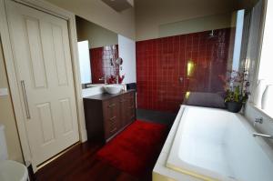 a bathroom with a tub and a sink and red tiles at Clement House in Benalla
