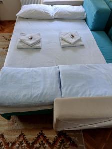 two beds with white sheets and towels on them at Apartman Bubamara in Arilje