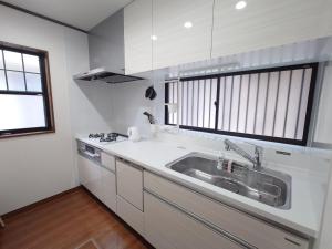 a white kitchen with a sink and a window at Chiba Gateway House in Chiba