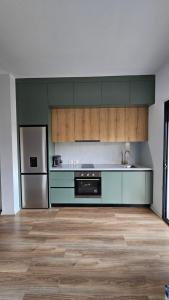 a kitchen with green cabinets and a stainless steel refrigerator at Modern apartment with sea views in Vlorë